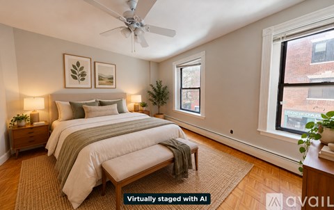 A bedroom with a bed, a nightstand, a window, and a plant.