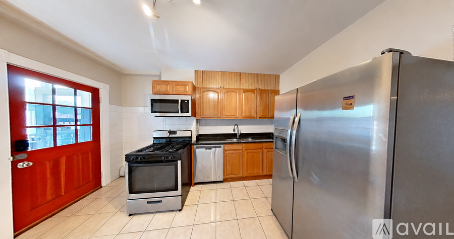 A kitchen with a red door and a stainless steel refrigerator.