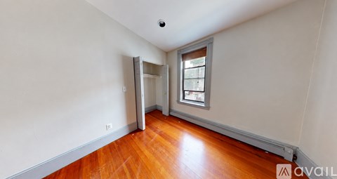 A room with a wooden floor and a window with a view of a building outside.