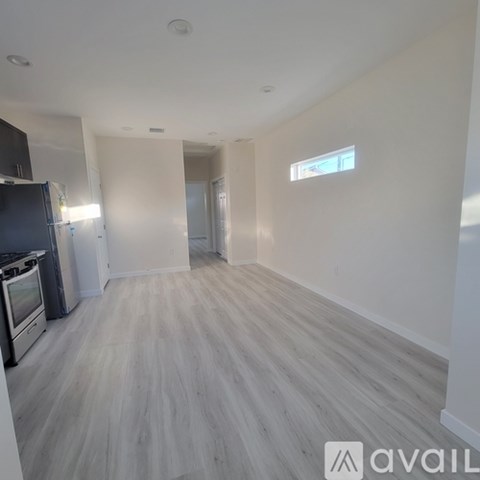 A spacious room with wooden flooring and a window.
