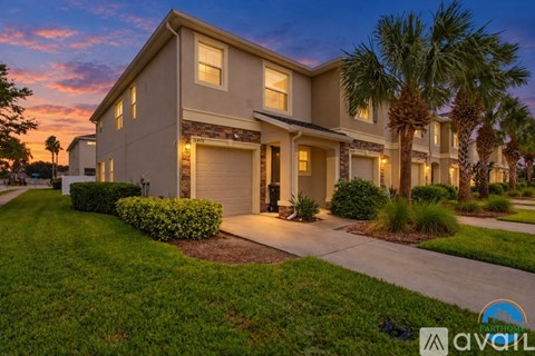 A modern house with a driveway and palm trees in front.