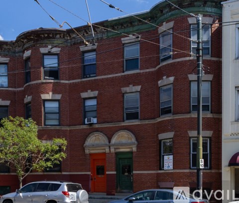 A red brick building with a green door and a tree in front.