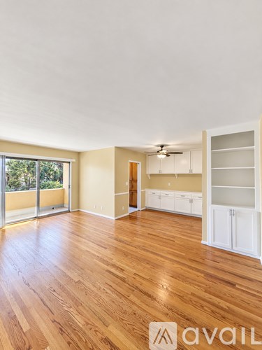 A room with wooden floors and a sliding glass door leading to a balcony.