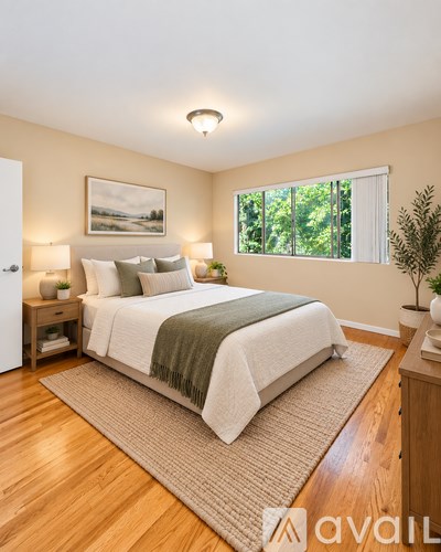 A bedroom with a large bed and a window overlooking trees.