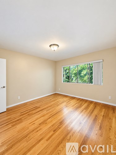 A room with wooden flooring and a window with blinds.