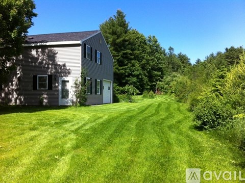 A house with a grey roof and a green lawn in front of it.