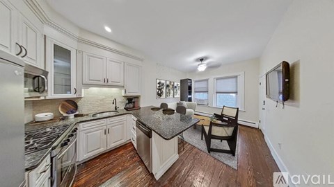 A kitchen with white cabinets and a black granite countertop.