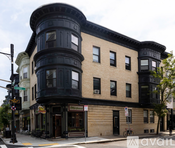 A street view of a corner building with a black awning and a bicycle parked in front.