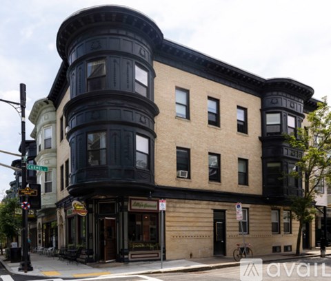 A street view of a corner building with a black awning and a bicycle parked in front.