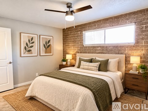 A bedroom with a brick wall and a bed with a green blanket.