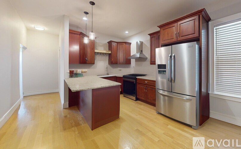 A kitchen with wooden cabinets and a stainless steel refrigerator.