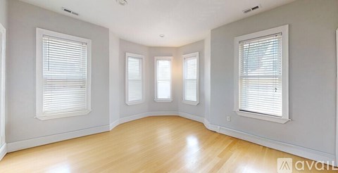 A room with wooden floors and three windows.