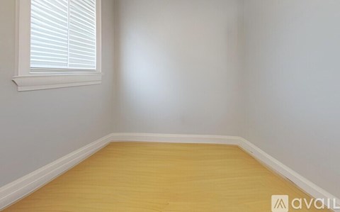 A room with wooden flooring and a window with blinds.