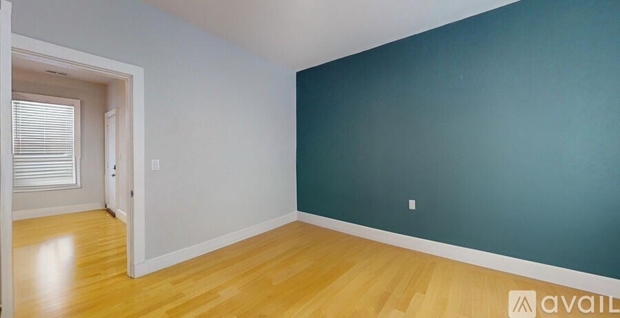 A room with a wooden floor and a doorway leading to another room.