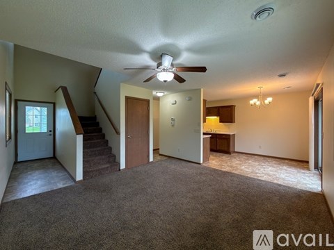 A living room with a carpeted floor and a ceiling fan.