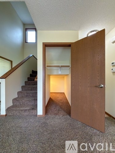 A wooden door is open to a hallway with a staircase.