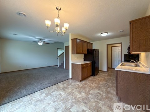 A well-lit kitchen with wooden cabinets and a black refrigerator.