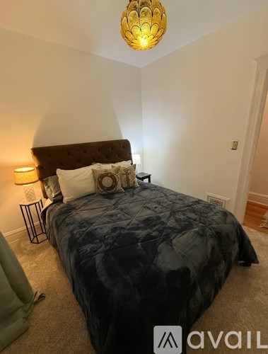 A bedroom with a large bed and a chandelier hanging from the ceiling.