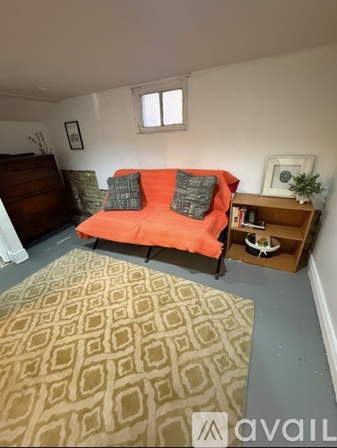 A living room with a couch, a rug, and a wooden cabinet.