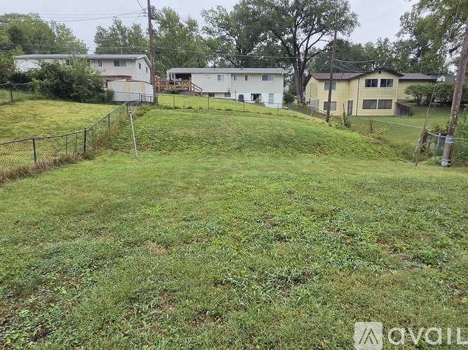 A grassy field with a fence and houses in the background.