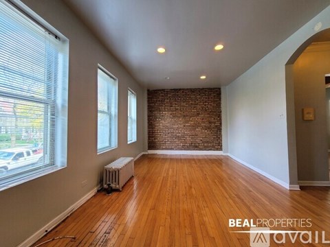A room with wooden floors and a brick wall is available for rent.