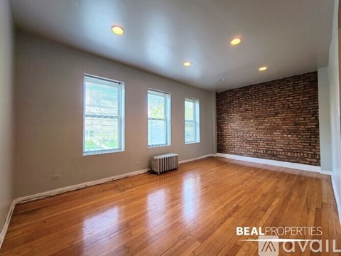 A room with wooden floors and a brick wall is available for rent.
