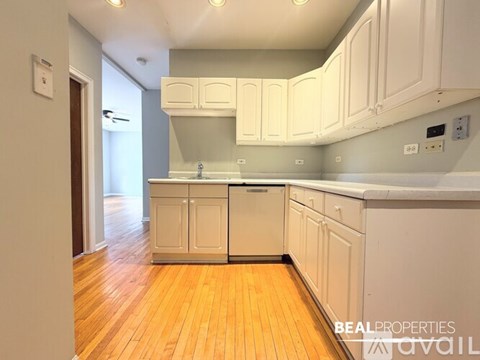 A kitchen with white cabinets and a wooden floor.