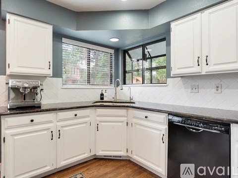 A kitchen with white cabinets and a black dishwasher.
