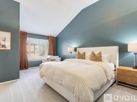 A bedroom with a large bed and a window with curtains.