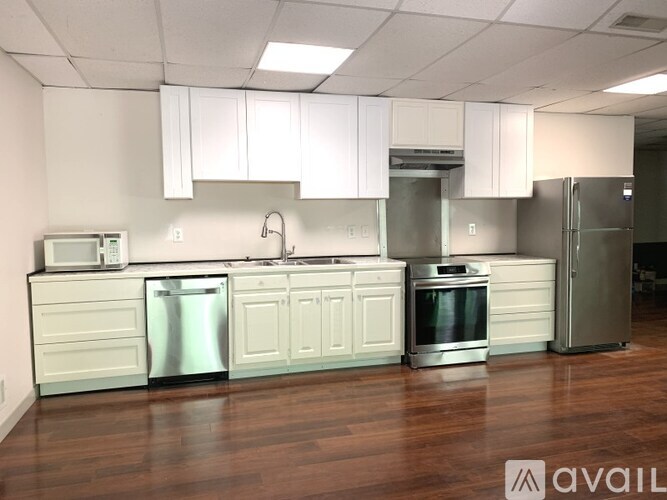 A kitchen with white cabinets and stainless steel appliances is available for rent.