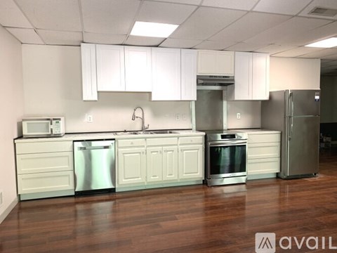 A kitchen with white cabinets and stainless steel appliances is available for rent.
