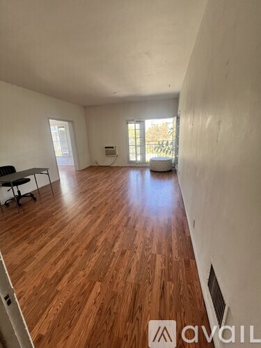 A room with wooden flooring and white walls.