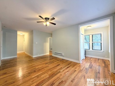 A spacious room with wooden flooring and a ceiling fan.
