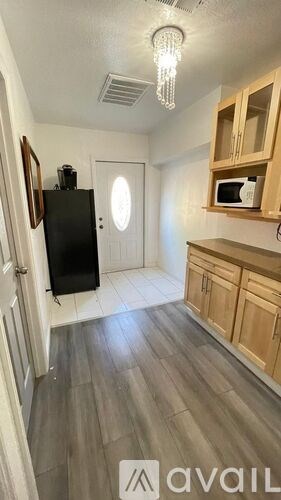 A kitchen with wooden cabinets and a black fridge.