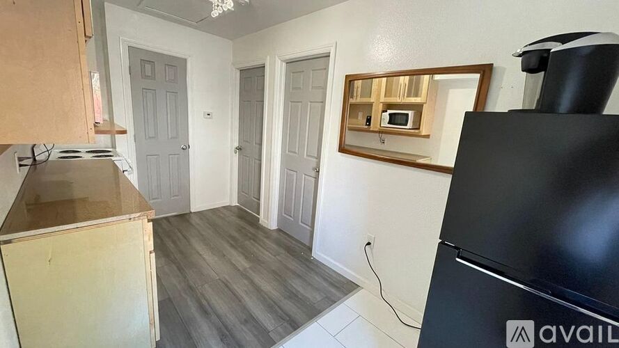A kitchen with a black fridge, wooden cabinets, and a microwave above the stove.