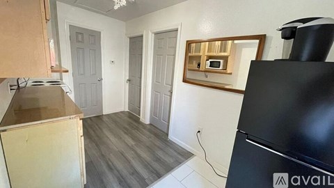 A kitchen with a black fridge, wooden cabinets, and a microwave above the stove.