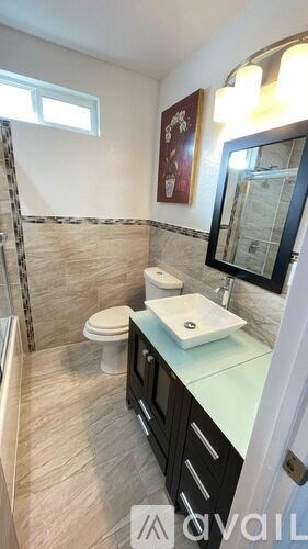 A bathroom with a toilet, sink, and mirror.