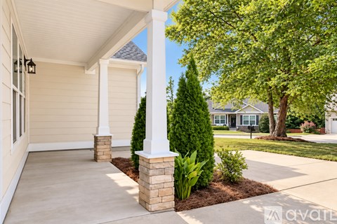 A house with a porch and a tree in front.