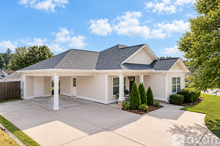 A white house with a black roof and a grey garage door.