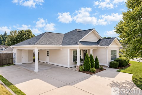A white house with a black roof and a grey garage door.