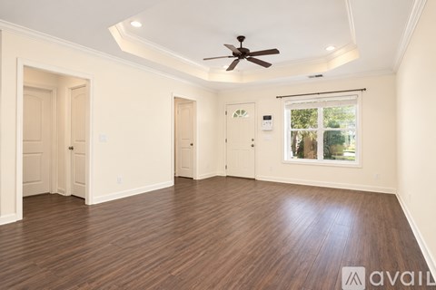 A spacious room with wooden flooring and a ceiling fan.