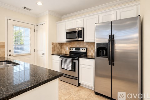 A kitchen with a black countertop and stainless steel appliances.