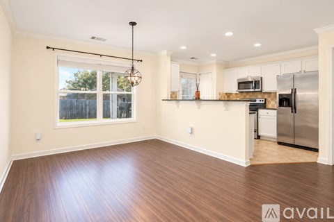 A kitchen with white cabinets and a wooden floor.