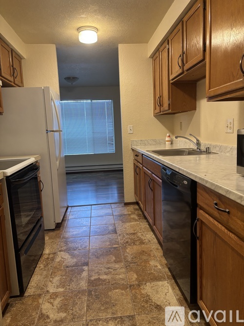 A kitchen with a white refrigerator and brown cabinets.