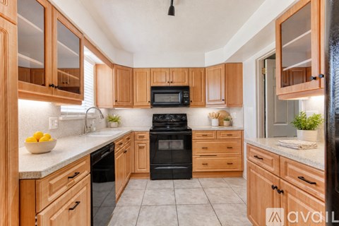 A kitchen with wooden cabinets and black appliances.