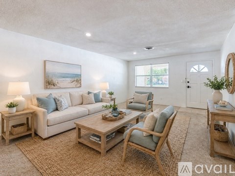 A living room with a white couch, a wooden coffee table, and a painting on the wall.
