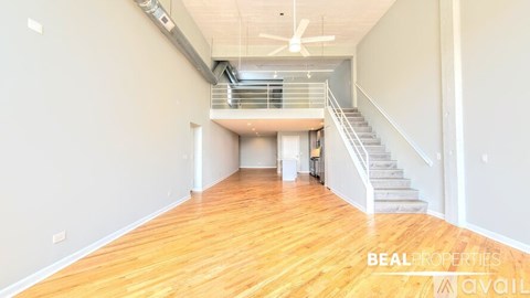 A spacious room with wooden flooring and a staircase leading to another level.