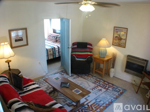 A living room with a striped couch and a fan.