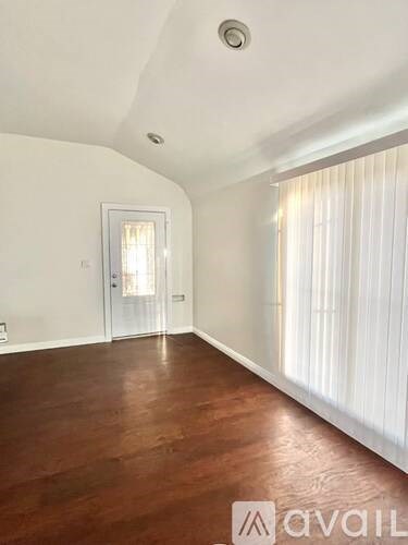 A room with wooden floors and a door leading to another room.