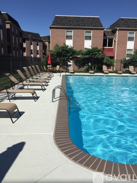 A pool with chairs around it and apartment buildings in the background.